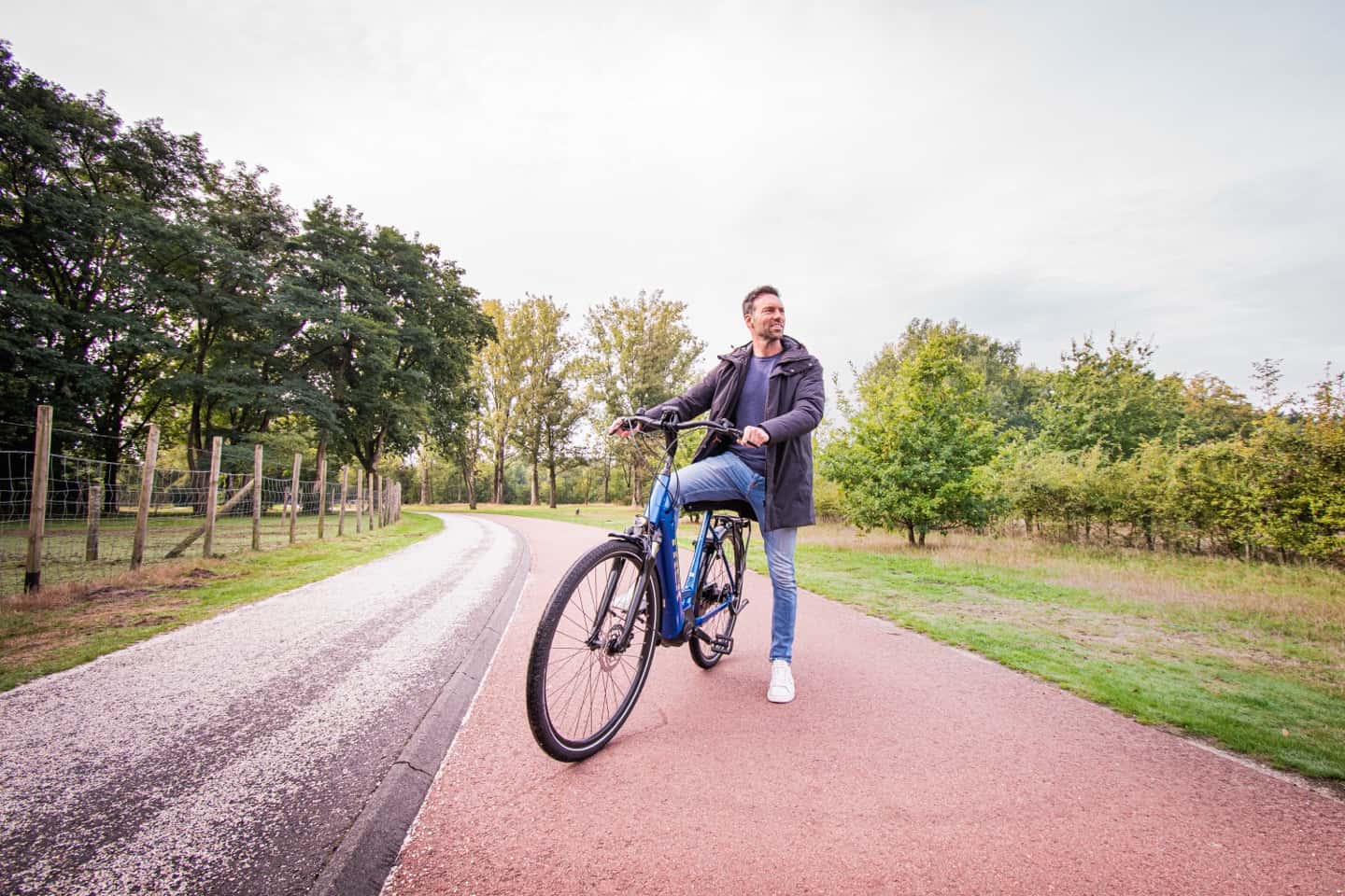 Man op een fiets, stilstaand op een fietspad